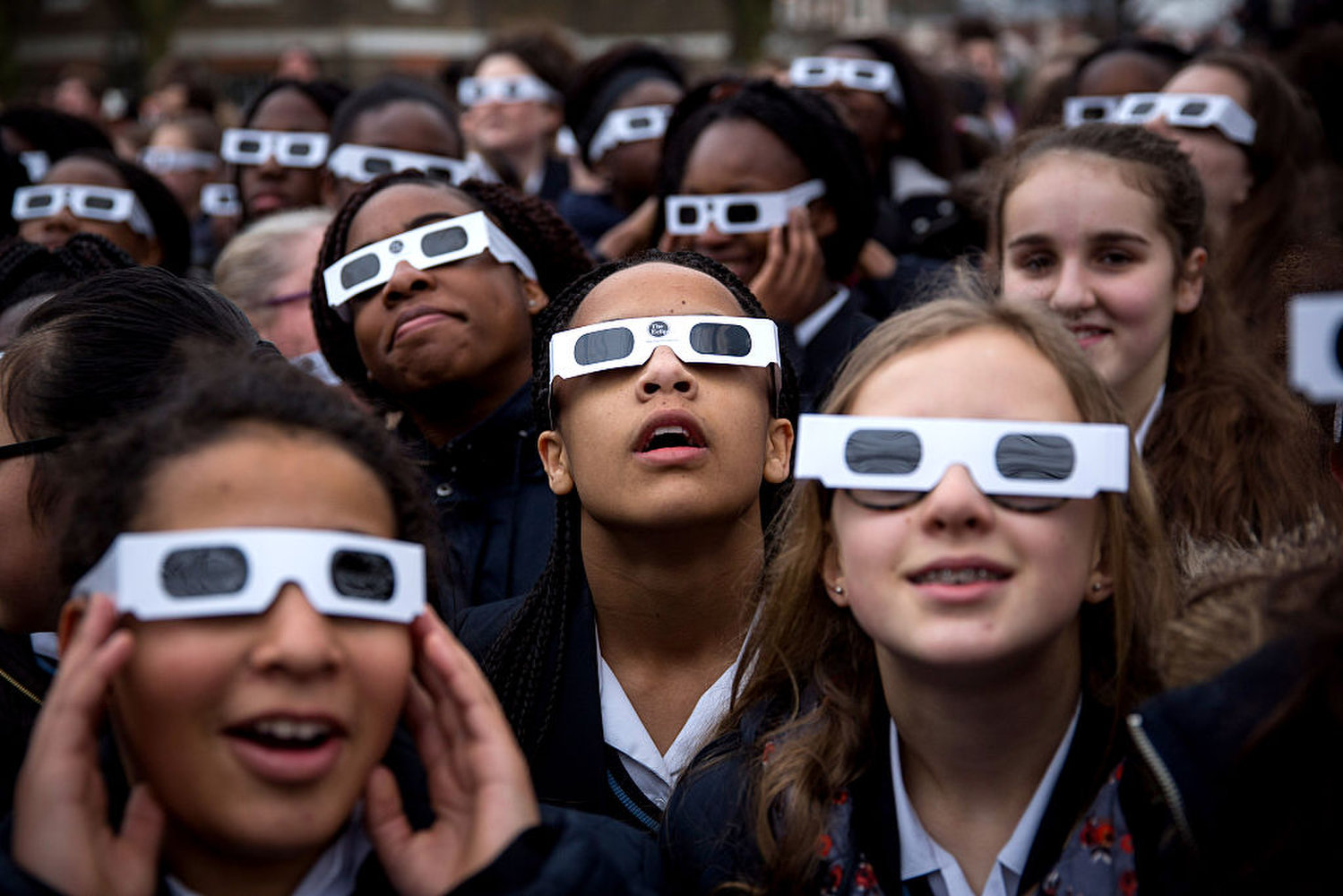 LONDON, UNITED KINGDOM - MARCH 20: Students from Saint Ursula's Covent Secondary School in Greenwich pose for a photograph wearing protective glasses at the Royal Observatory Greenwich on March 20, 2015 in London, England. Hundreds of people gathered outside The Royal Observatory Greenwich hoping see a near total solar eclipse. The solar eclipse, which occurs when the Moon passes between the Sun and the Earth, started at 08:24 GMT and continues until 10:41 GMT, with the maximum obscuration of the Sun happening at 09:31 GMT. The last significant solar eclipse visible from the UK was on 11 August, 1999. (Photo by Rob Stothard/Getty Images)